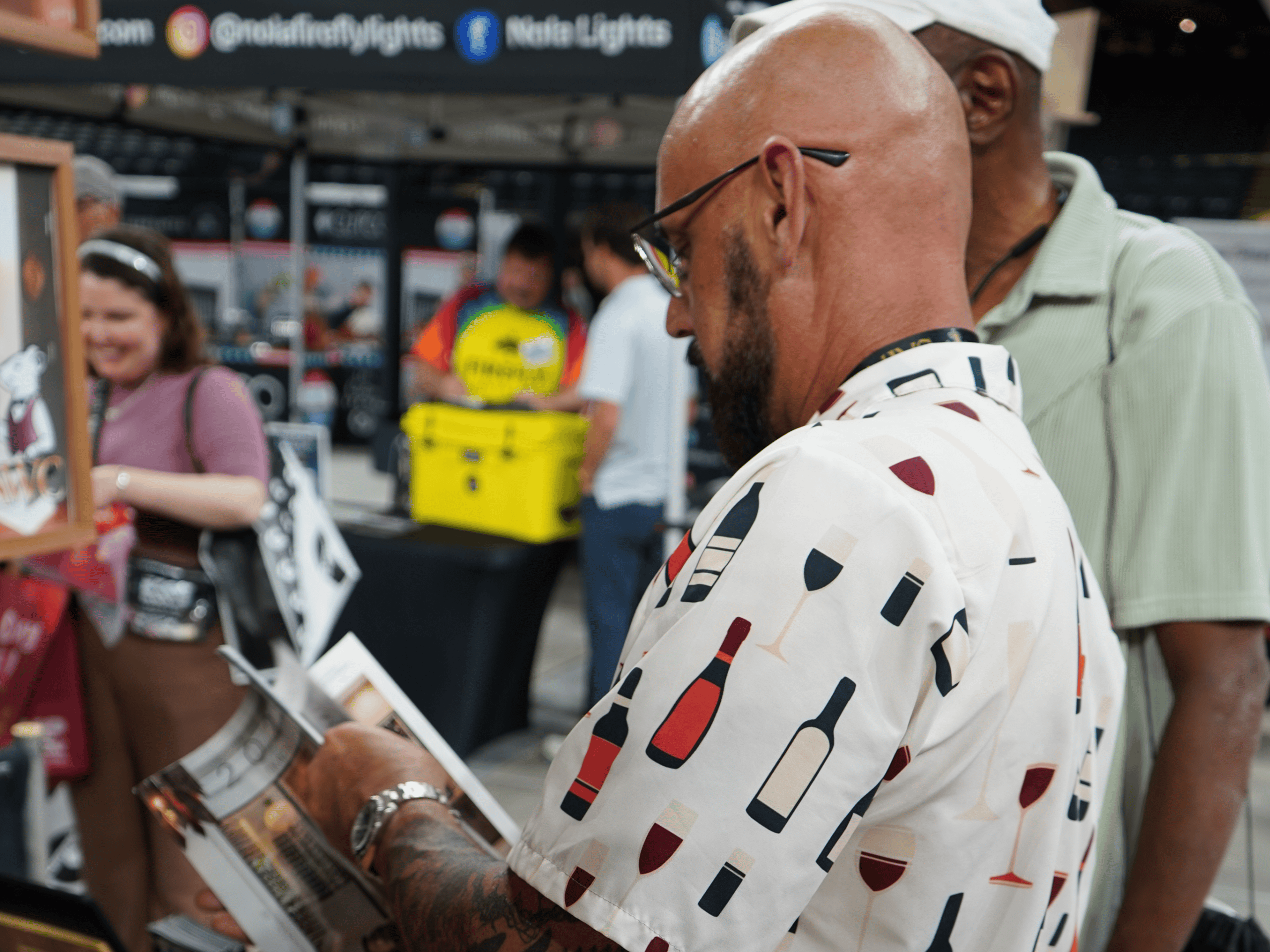 Man tasting wine at a wine event with people in the background.