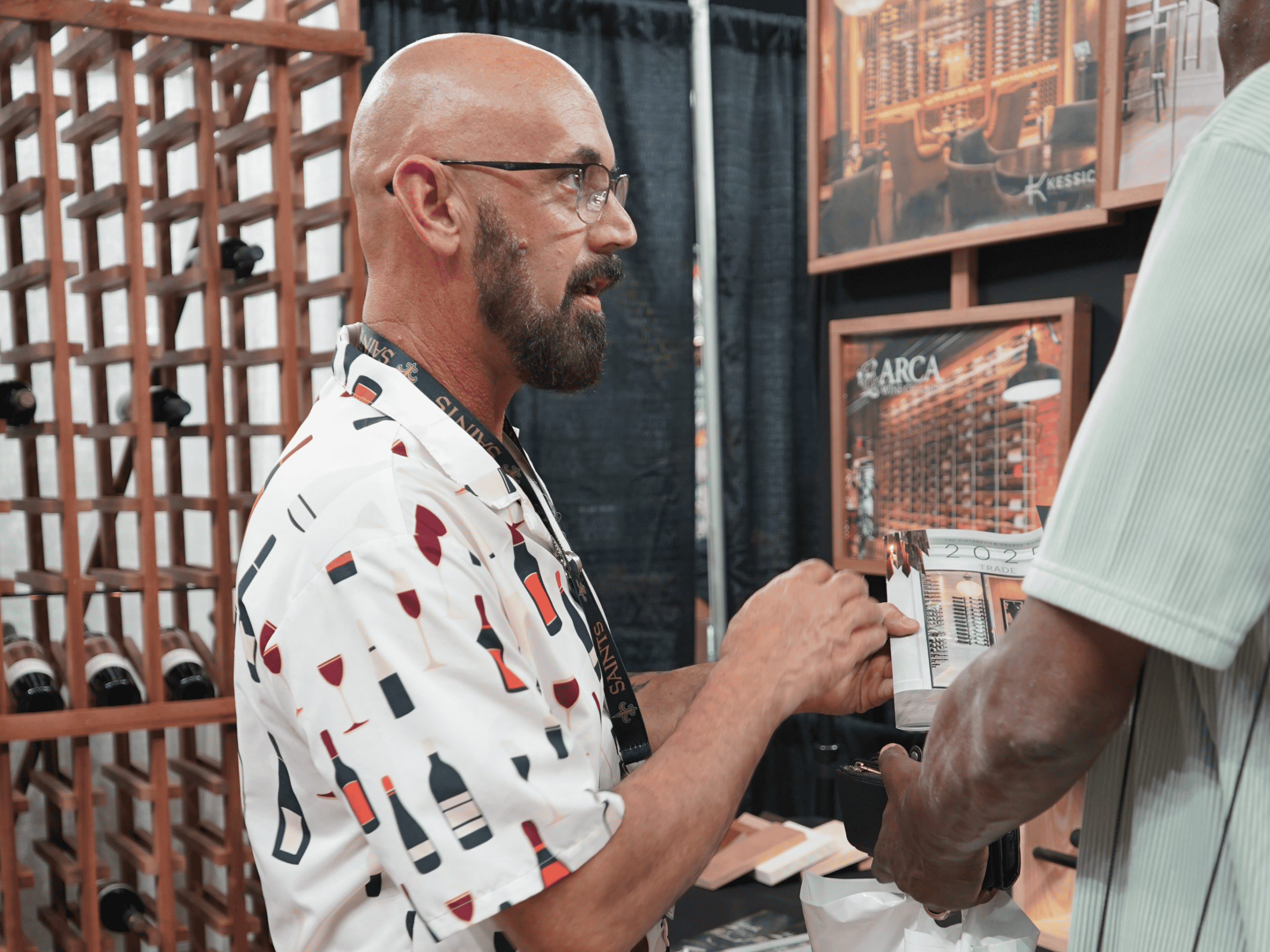 Man with glasses and beard tasting wine at Example Co booth.