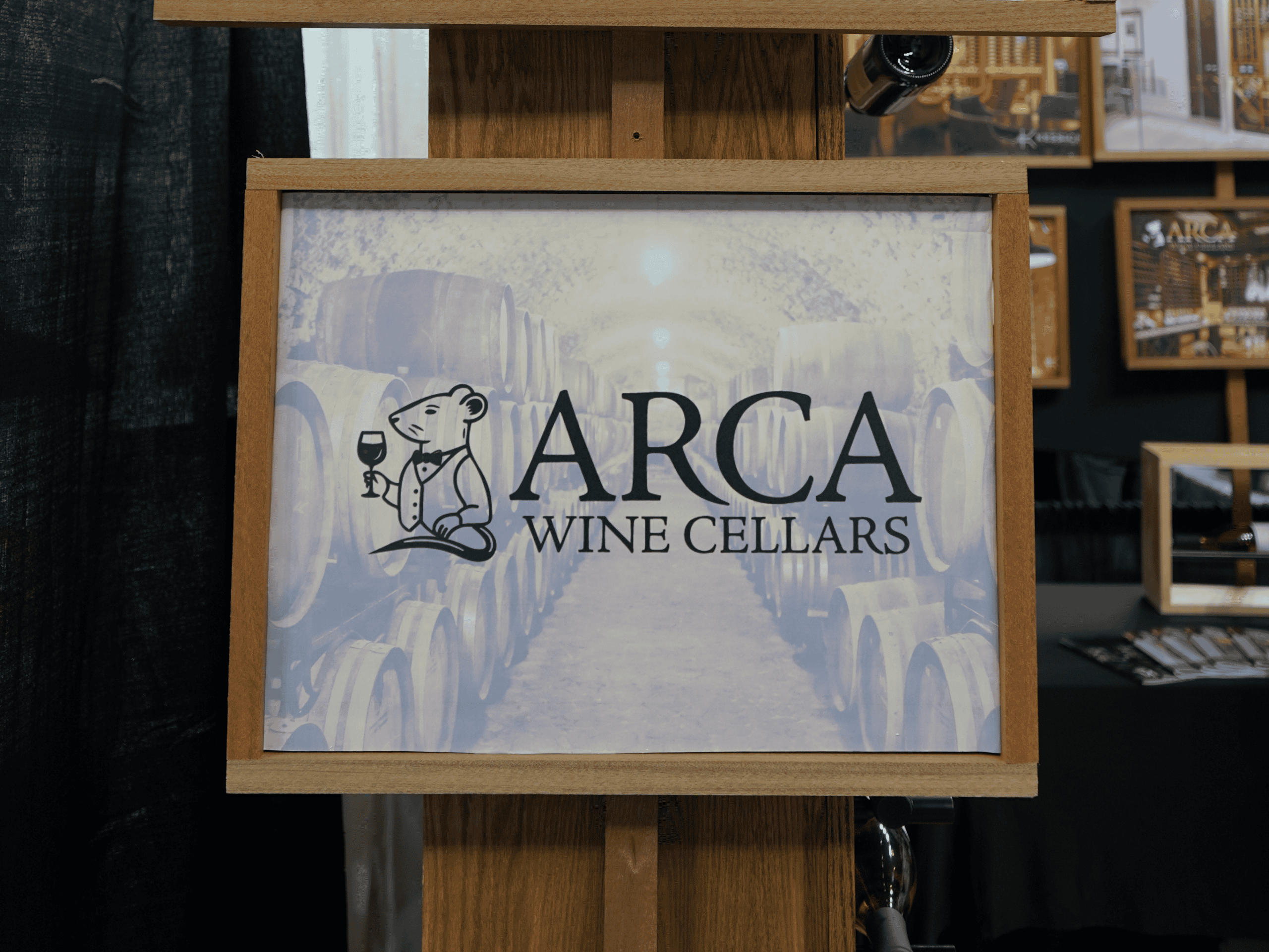 ARCA Wine Cellars sign with wine barrels background, showcasing wine storage expertise.