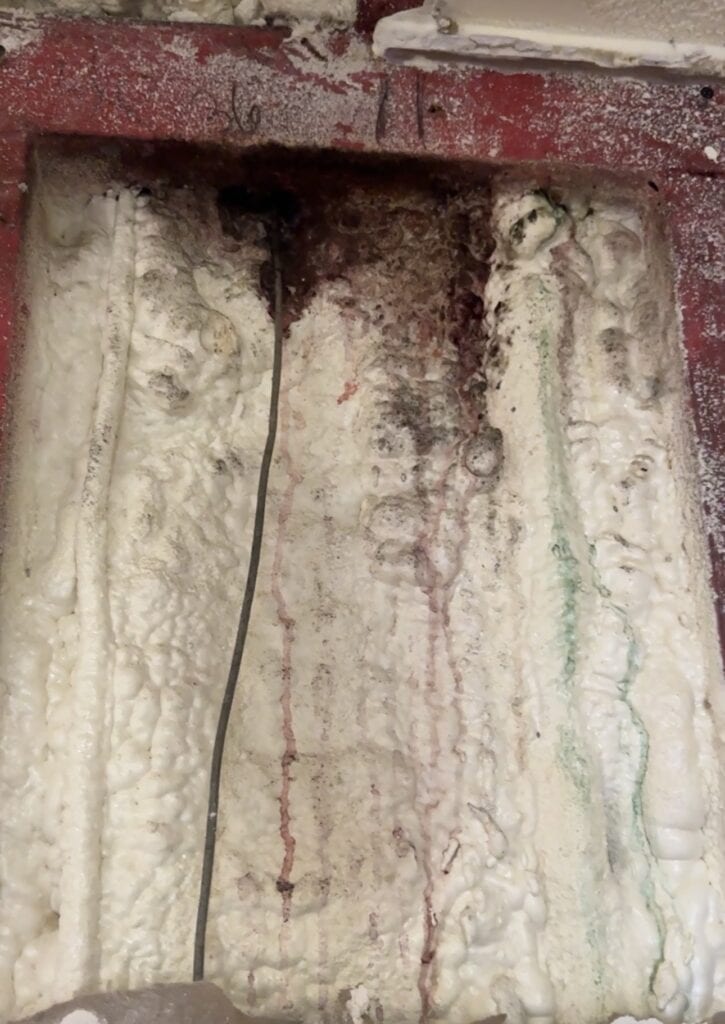 Vertical moisture staining running down the inside of a wine cellar wall cavity